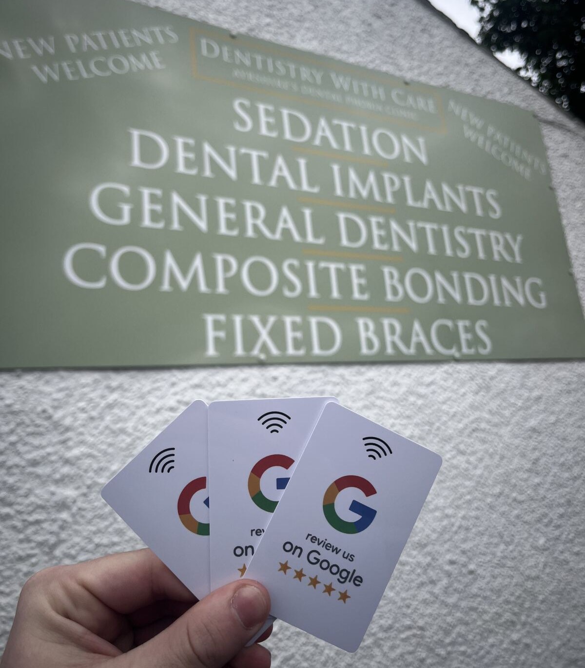 NFC review cards held up outside Dentistry With Care in Ayrshire